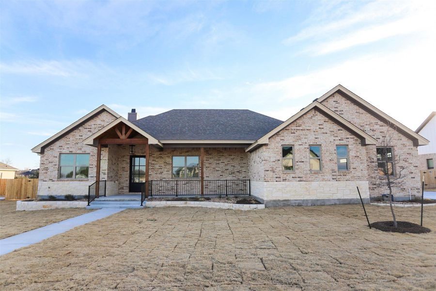 View of front of home with covered porch, brick siding, and a chimney