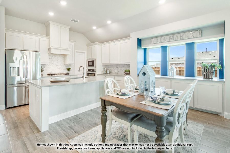 Open kitchen and dining area with white cabinets, large island, stainless appliances, and wood dining table near bay window
