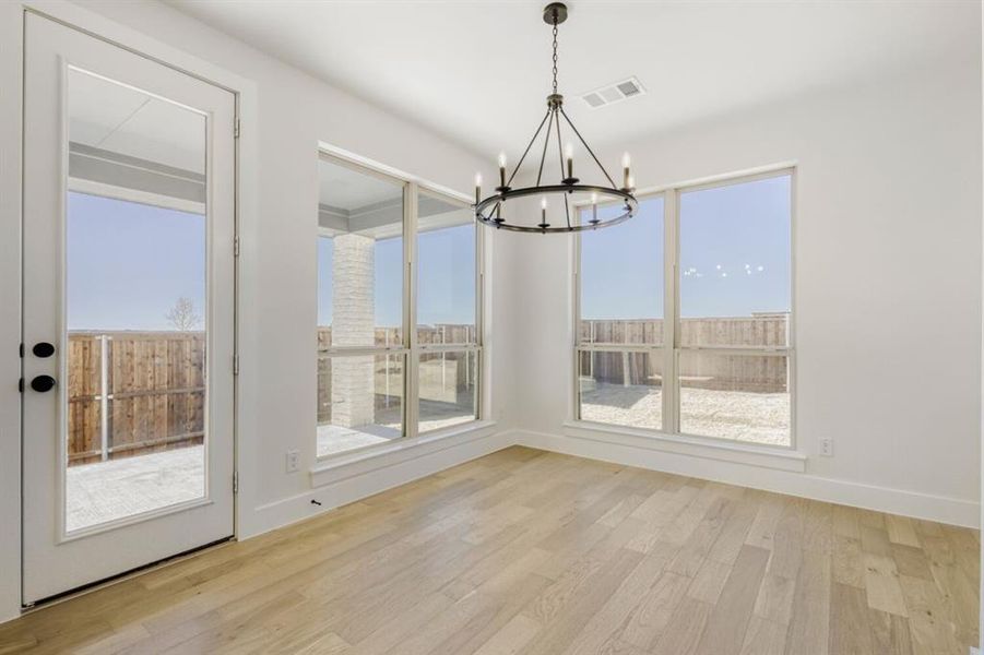 Unfurnished dining area featuring light wood-style floors and hanging lights