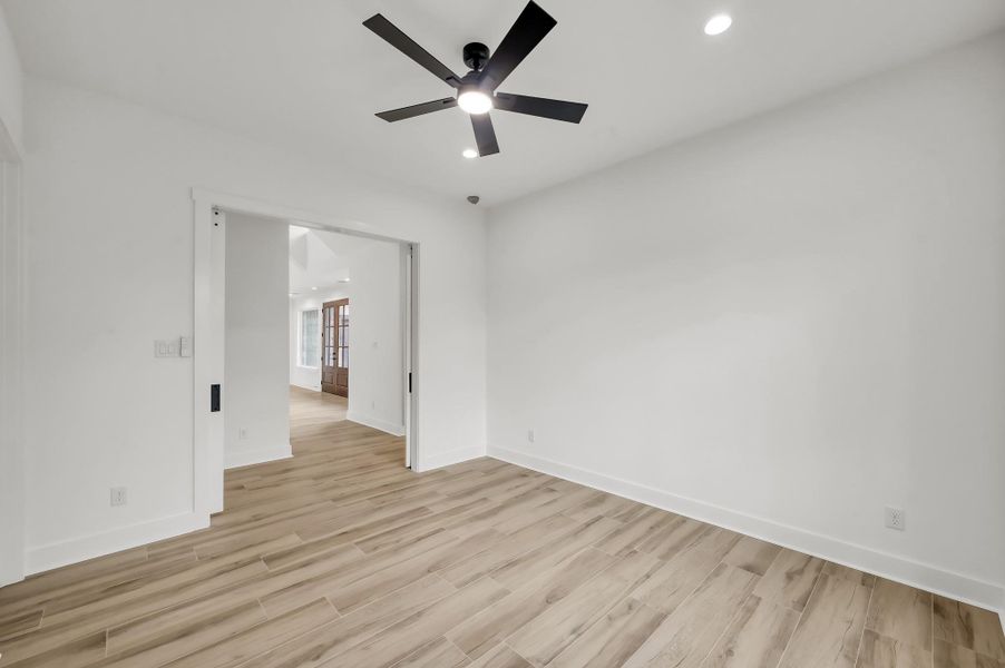 Spacious secondary bedroom featuring modern finishes, recessed lighting, and sliding barn doors that connect easily to the main living areas.