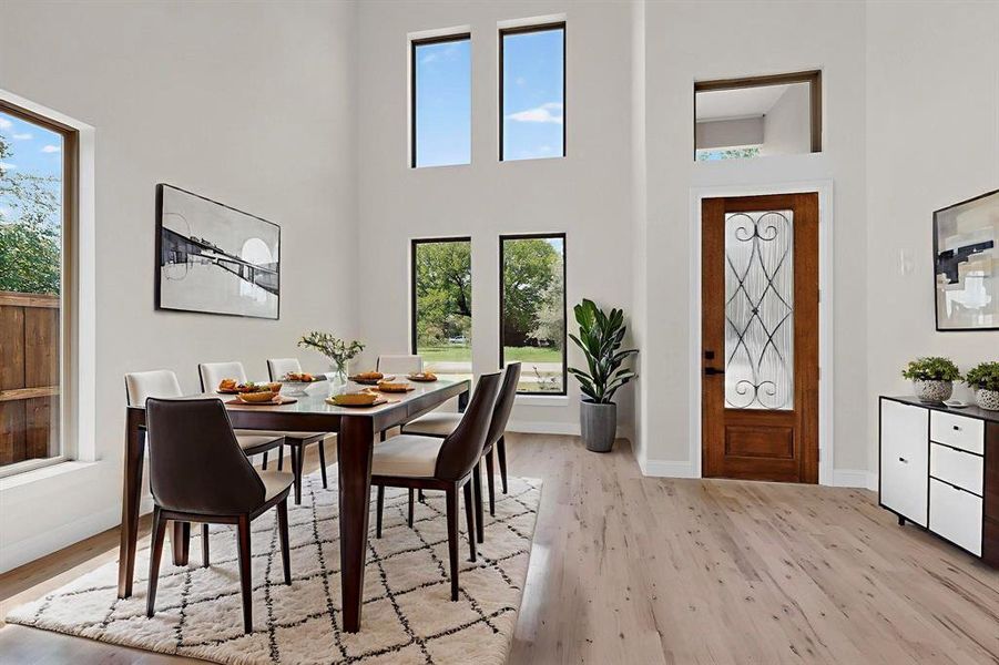 Dining area with light wood-style flooring and a towering ceiling Dining area with light wood-style flooring and a towering ceiling