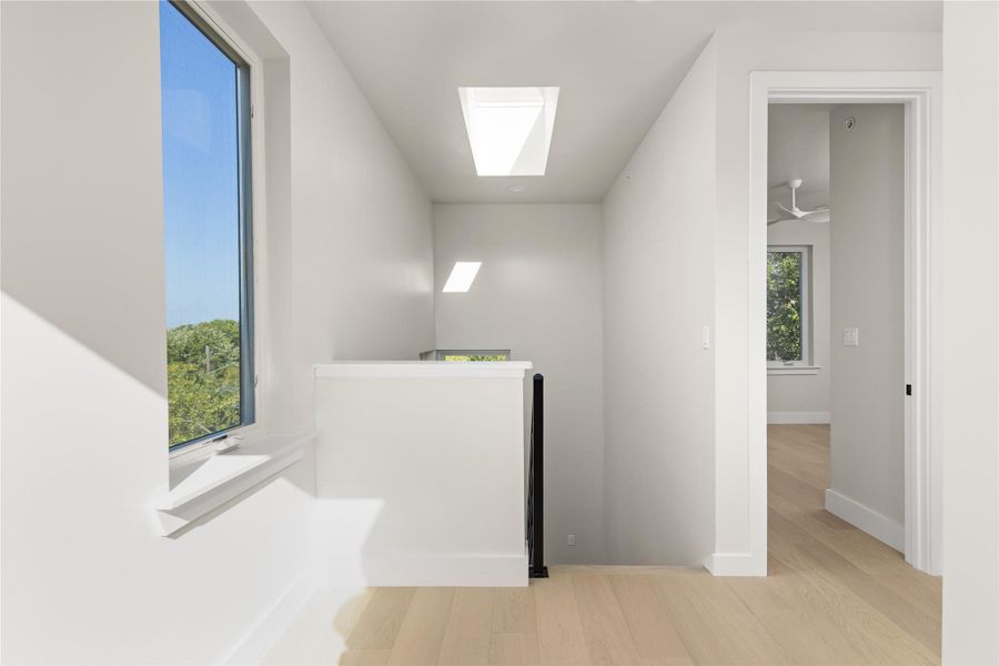 Natural light streams through overhead skylights and expansive windows in this upper-level landing.