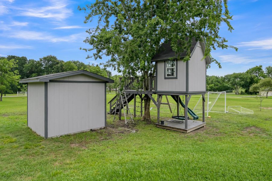 charming treehouse with a slide, a small storage shed