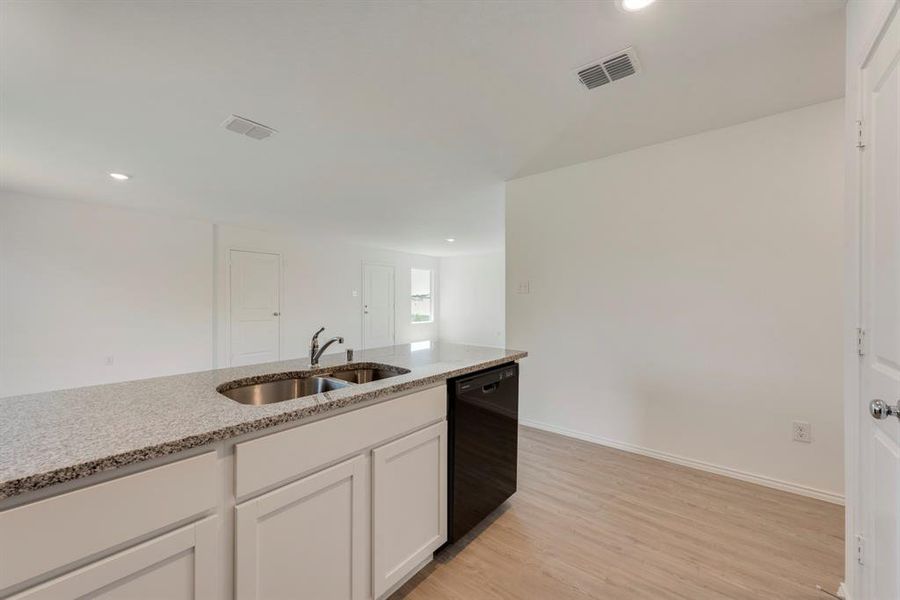 Kitchen featuring light hardwood / wood-style floors, white cabinets, sink, and dishwasher