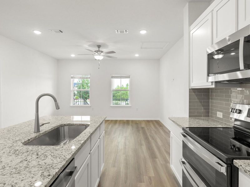 A well-appointed kitchen features a large granite island and modern stainless steel appliances, opening to a spacious living area.