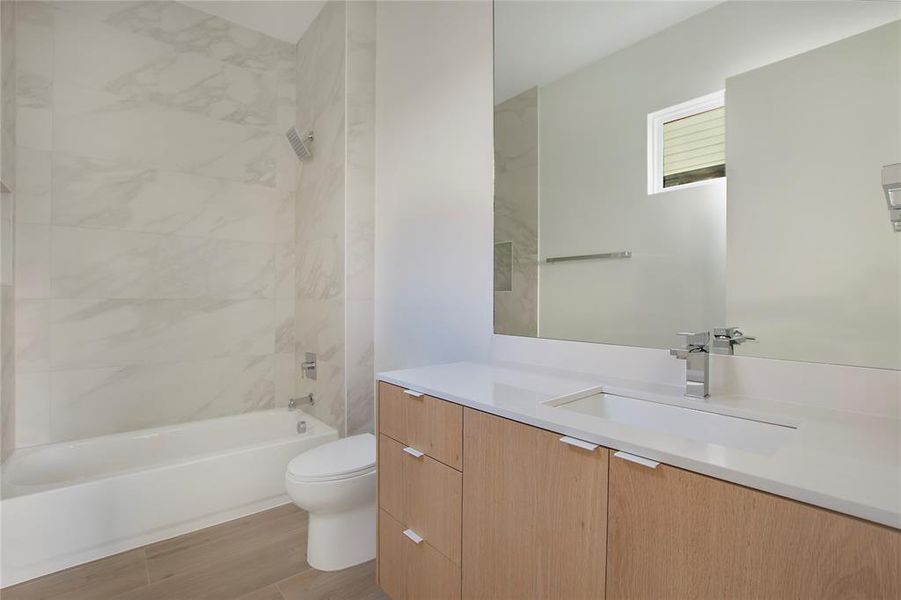 Full bathroom with hardwood / wood-style flooring, toilet, vanity, and tiled shower / bath