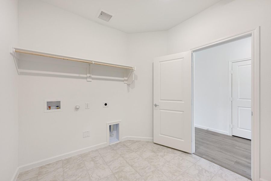 Empty laundry room with wall-mounted shelf, washer and dryer hookups, and tile flooring Empty laundry room with wall-mounted shelf, washer and dryer hookups, and tile flooring
