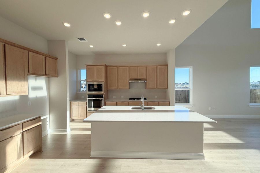Kitchen with recessed lighting, appliances with stainless steel finishes, a center island with sink, light wood-type flooring, and plenty of natural light