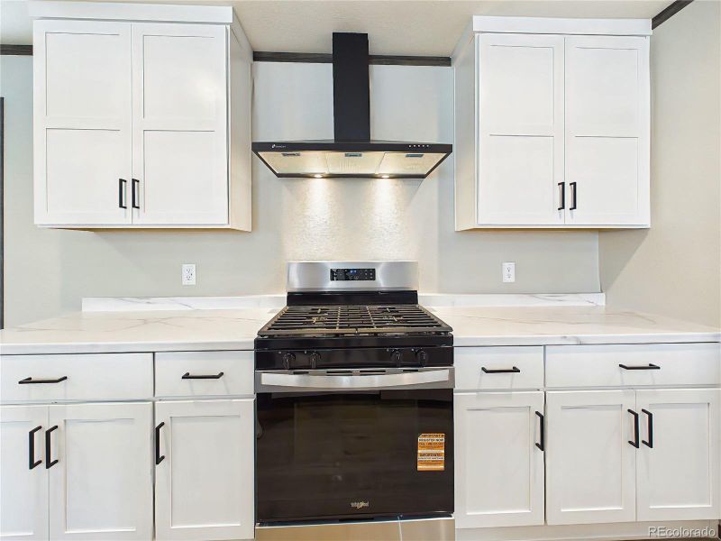 Kitchen – Updated kitchen with sleek countertops, gas range, and vent hood, complemented by clean-lined cabinetry and contemporary finishes.