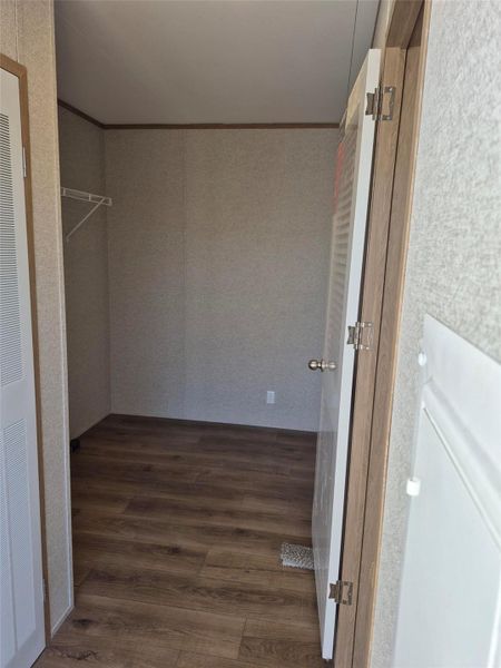 Walk in closet with dark wood-style floors and a heating unit