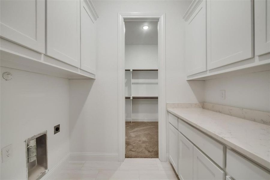 Laundry room featuring cabinet space and light carpet