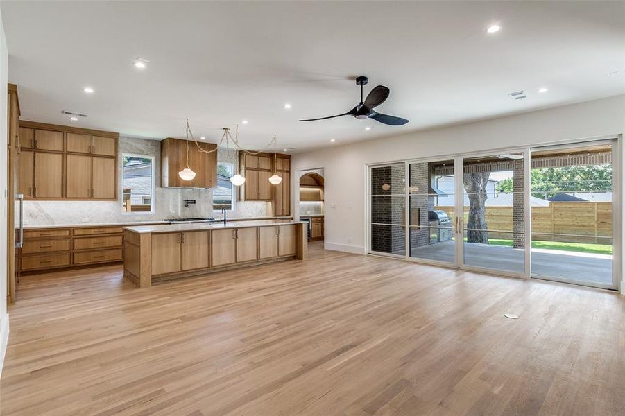 Kitchen with light wood-style floors, tasteful backsplash, a center island with sink, decorative light fixtures, and recessed lighting Kitchen with light wood-style floors, tasteful backsplash, a center island with sink, decorative light fixtures, and recessed lighting