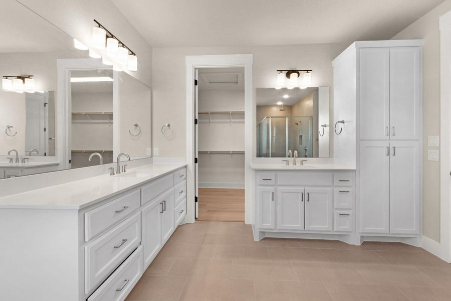 Full bathroom with two vanities, a spacious closet, and a stall shower