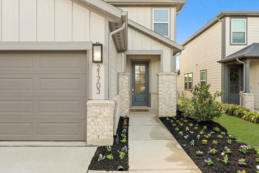 Approaching the front door you see the detailed craftsman exterior with light neutral brick and freshly updated landscaping. It's complete with a modern lantern and painted front door.