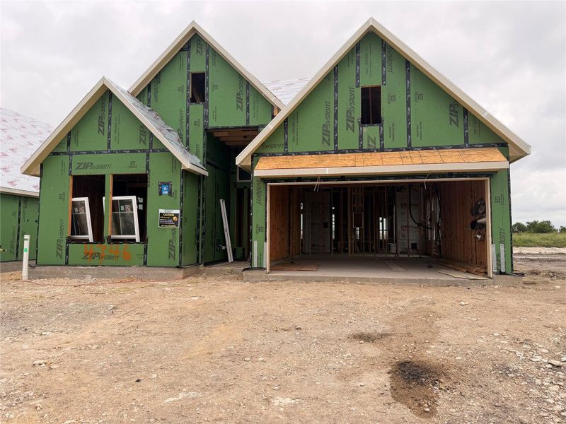 A newly framed residence poised for completion, featuring a spacious two-car garage opening.