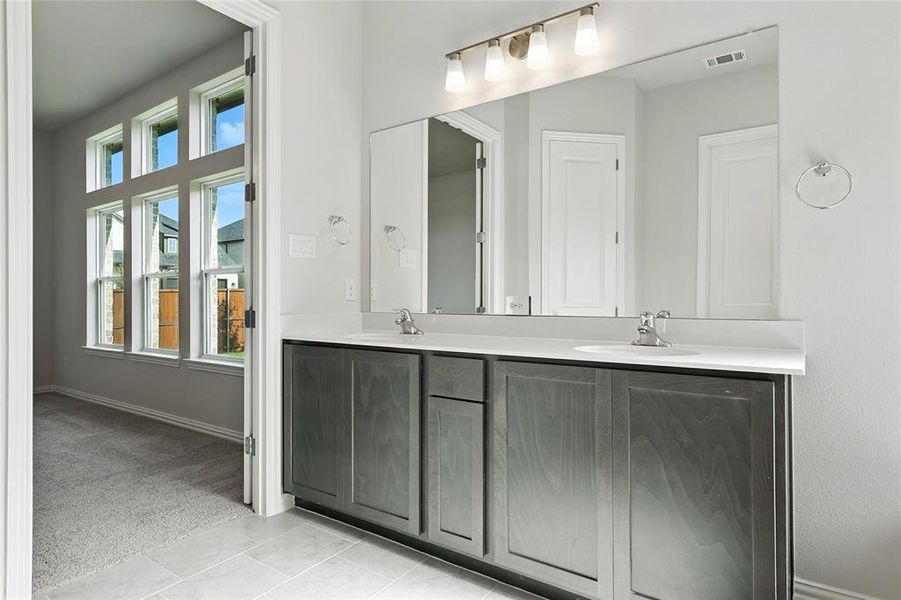 Bathroom featuring double vanity, light carpet, and light tile patterned flooring