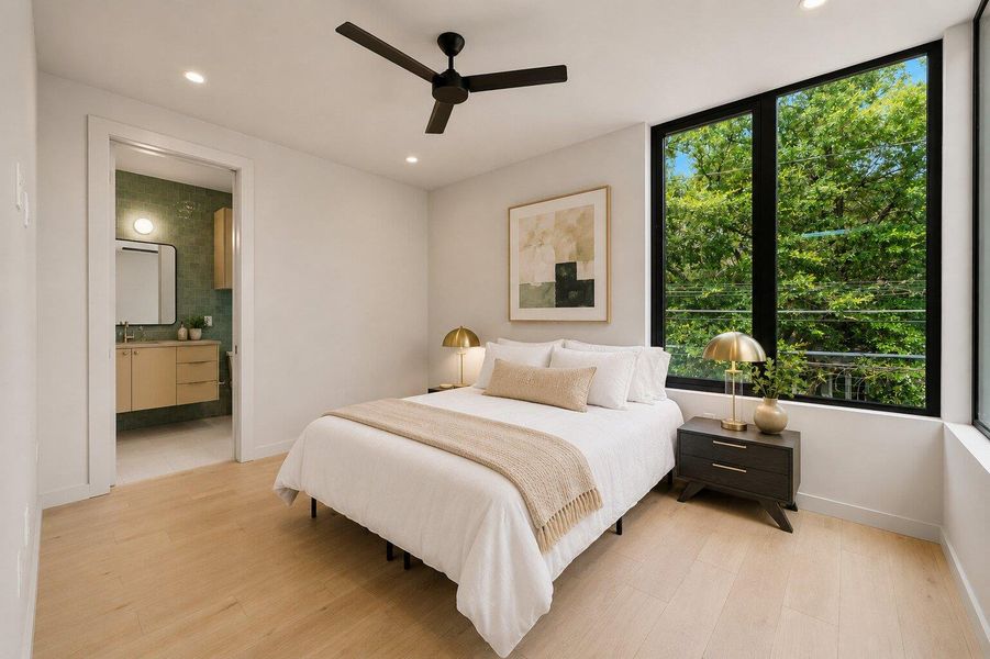 A tranquil bedroom retreat features broad windows framing verdant foliage and a seamless connection to a modern bathroom. A tranquil bedroom retreat features broad windows framing verdant foliage and a seamless connection to a modern bathroom.