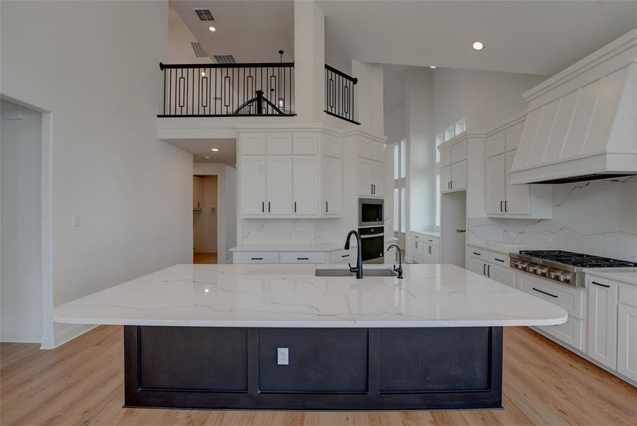 Kitchen with a sink, visible vents, white cabinets, appliances with stainless steel finishes, and custom exhaust hood