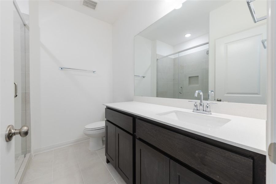 Full bath with vanity, a shower stall, and light tile patterned flooring