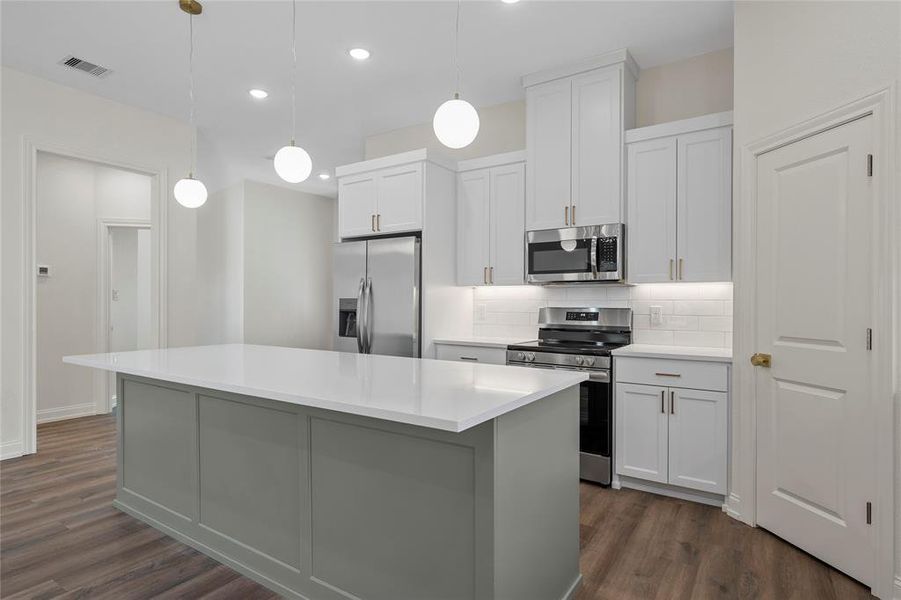 Kitchen with white cabinetry, appliances with stainless steel finishes, decorative backsplash, pendant lighting, and dark wood-style floors Kitchen with white cabinetry, appliances with stainless steel finishes, decorative backsplash, pendant lighting, and dark wood-style floors