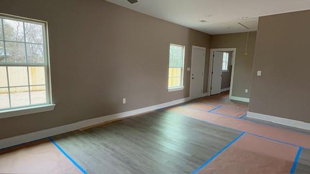 Spare room featuring attic access, wood finished floors, and baseboards