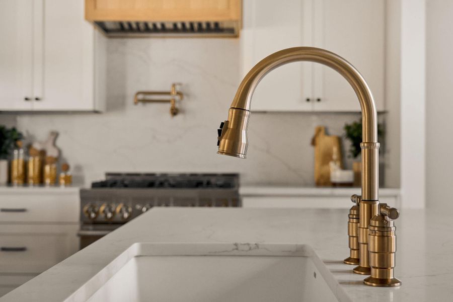 Kitchen view of white cabinets, pot filler, decorative backsplash, and light stone countertops Kitchen view of white cabinets, pot filler, decorative backsplash, and light stone countertops