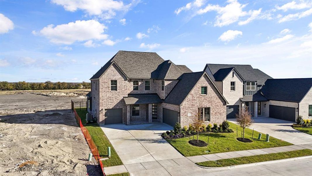 View of front facade with brick siding, driveway, an attached garage, a shingled roof, and a front yard