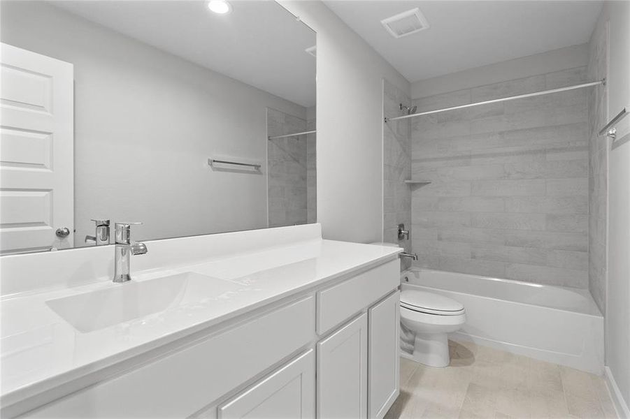 Secondary bath features tile flooring, bath/shower combo with tile surround, white stained wood cabinets, beautiful light countertops, mirror, sleek fixtures and modern finishes.