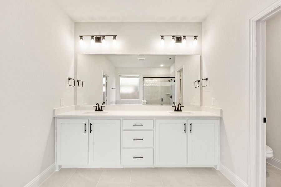 Bathroom with double vanity, white cabinets, dual sinks, large mirror, and black hardware fixtures Bathroom with double vanity, white cabinets, dual sinks, large mirror, and black hardware fixtures