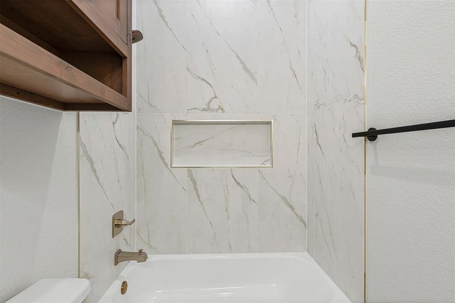 Full bath featuring washtub / shower combination and a textured wall Full bath featuring washtub / shower combination and a textured wall