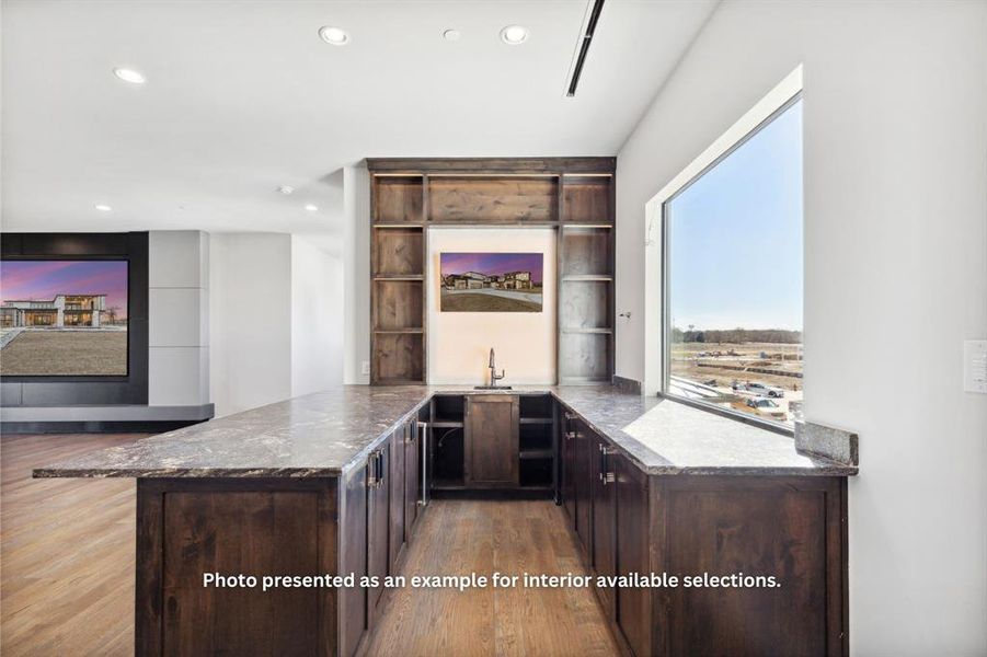 Bar with light hardwood / wood-style floors, sink, dark stone countertops, and dark brown cabinets