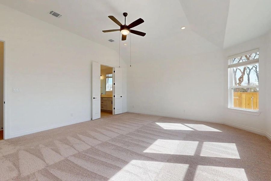 Spacious room featuring vaulted ceilings, a window providing natural light, and carpeted flooring