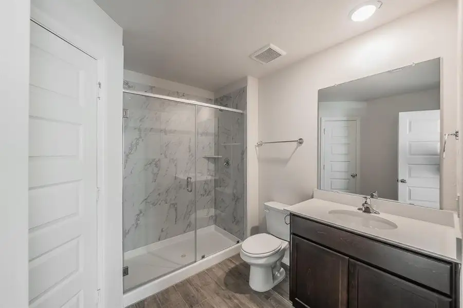 Full bath featuring a marble finish shower, vanity, and dark wood-type flooring Full bath featuring a marble finish shower, vanity, and dark wood-type flooring