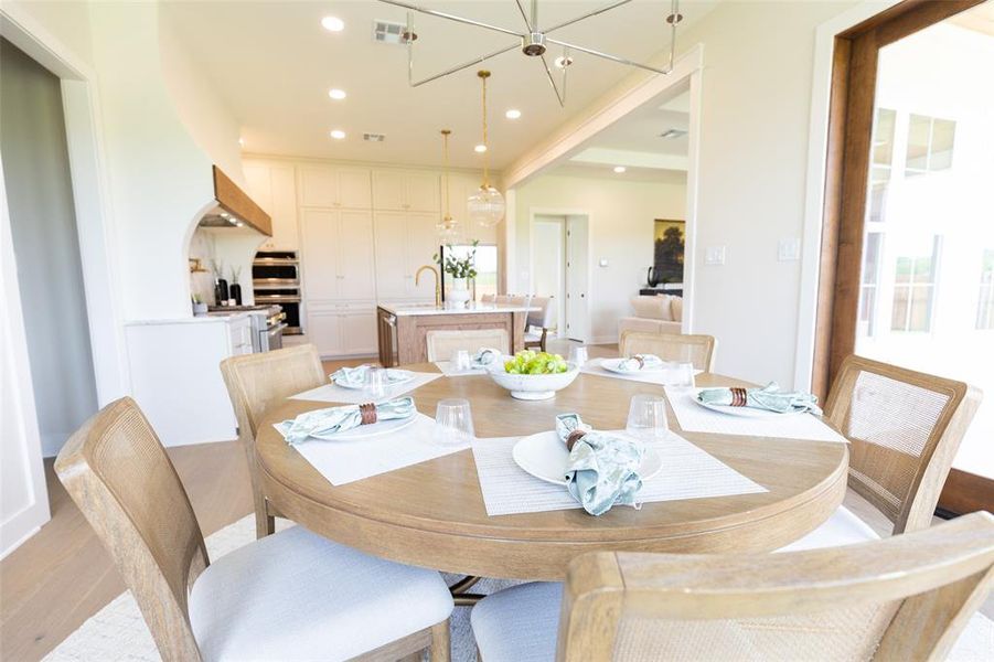 Open-concept dining area featuring a light wood-finish dining table and wood-finish flooring