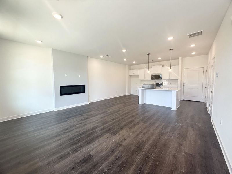 Unfurnished living room featuring recessed lighting, dark wood-style floors, and a glass covered fireplace
