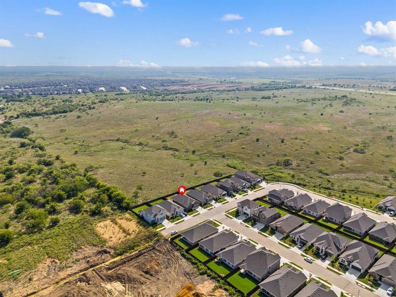 Aerial view of the neighborhood with the property marked, showing its private setting backing up to wide open green space.