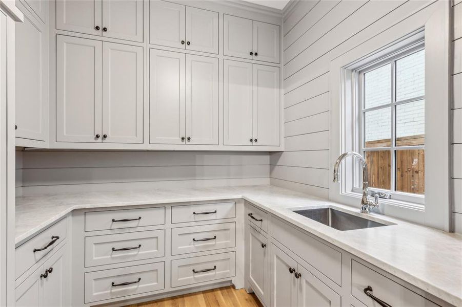 Kitchen with light wood-type flooring, a sink, white cabinetry, and light stone countertops