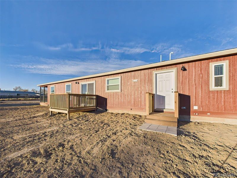 The rear of the home includes a simple back entry with steps and a modest landing, overlooking a wide open lot ready for personalization.