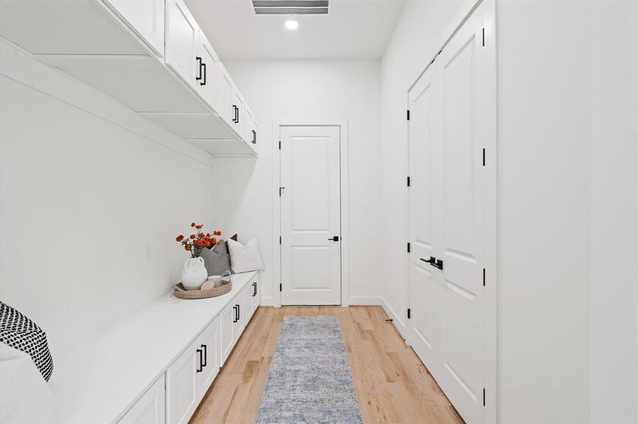 Mud room with bench seating and storage. On the right is the pantry, and straight ahead is the garage.