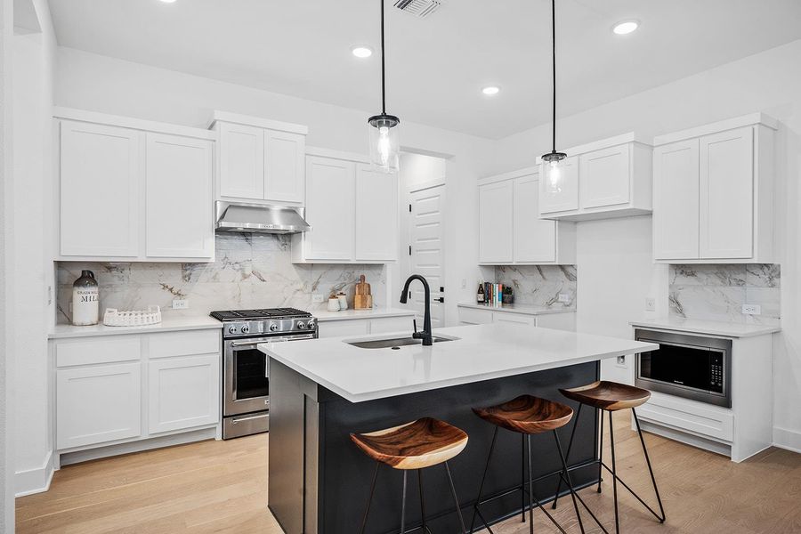 Modern kitchen with stainless steel appliances, breakfast bar and pantry off laundry room.
