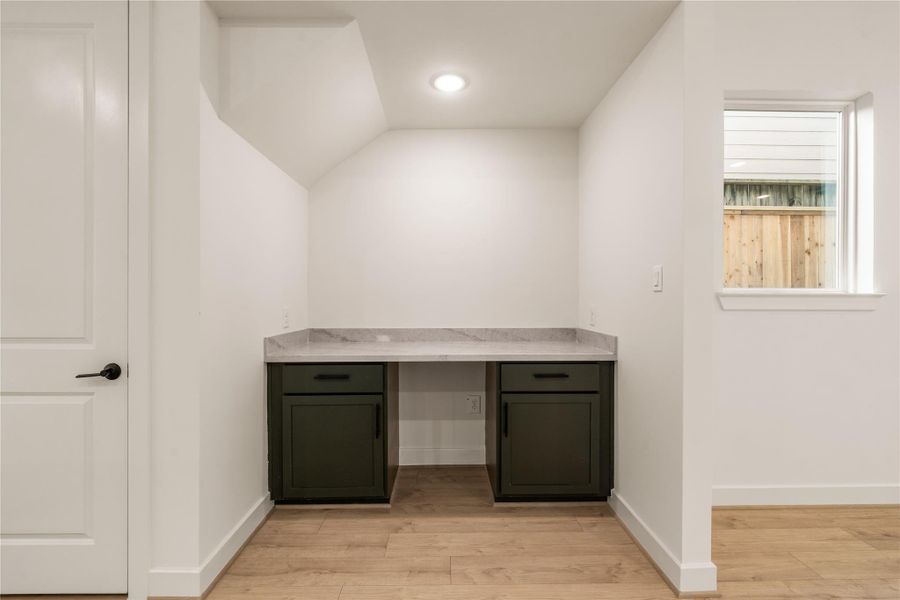 Built-in pocket office — custom desk niche featuring dark cabinetry, quartz countertop, and dedicated window for natural light while working.