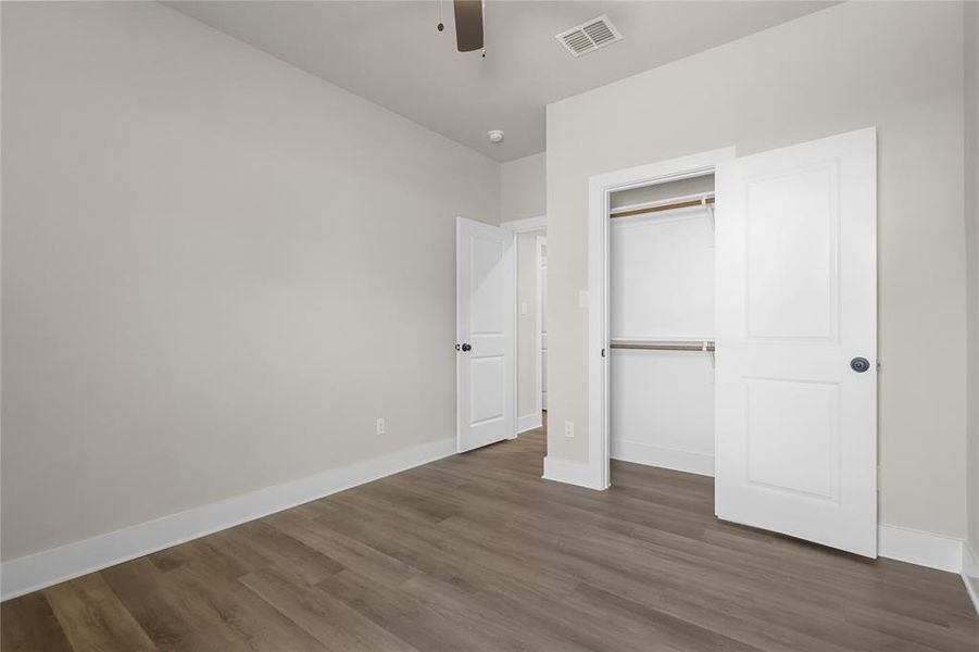 Unfurnished bedroom with ceiling fan, dark hardwood / wood-style floors, and a closet