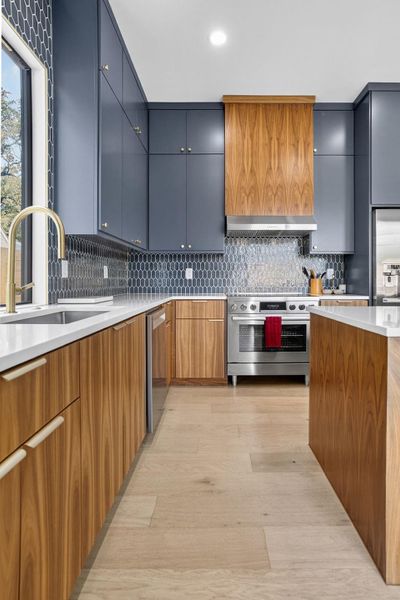 Kitchen with stainless steel appliances, light wood finished floors, decorative backsplash, light stone countertops, and recessed lighting