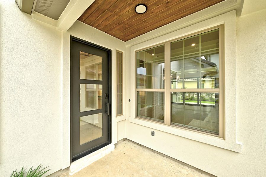 Entryway featuring a dark-framed door with multiple glass lites, a matching sidelite, and a large window with grilles