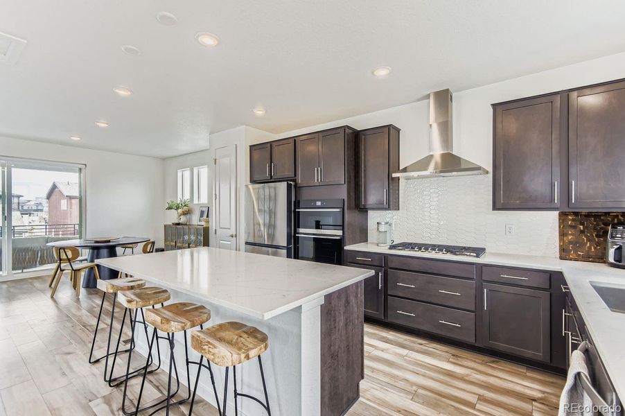 The spacious gourmet kitchen showcases upgraded cabinetry, a statement island, generous dining area, and a thoughtfully designed open flow into the living room—creating a bright and connected main living space.