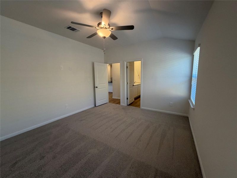 Unfurnished bedroom featuring carpet, vaulted ceiling, ceiling fan, and connected bathroom