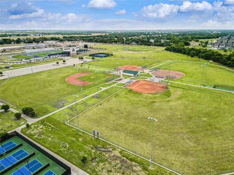 Expansive athletic complex featuring multiple baseball fields, tennis courts, and a football stadium