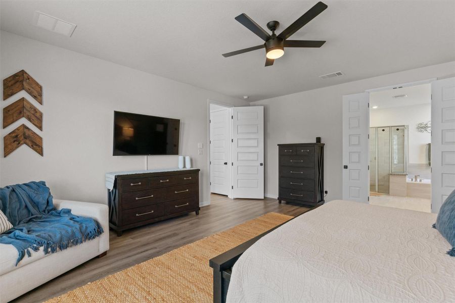 Bedroom featuring wood finished floors, a ceiling fan, and ensuite bathroom
