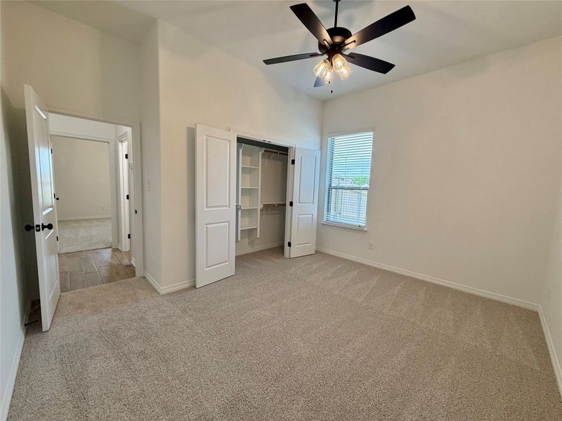 Carpeted room with vaulted ceiling and a ceiling fan