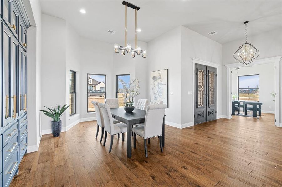 Dining room featuring a towering ceiling, a chandelier, and hardwood / wood-style floors